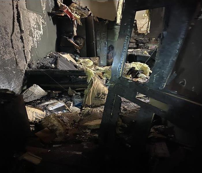 A back room with couch, lockers, and table turned black and charred from fire damage