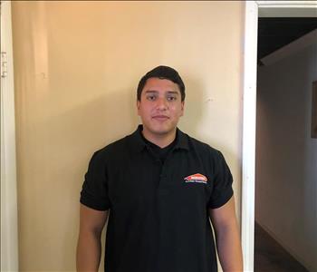 Male crew member in front of tan wall in SERVPRO shirt